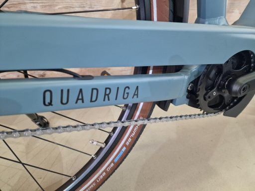 Ein Fahrradrahmen mit der Aufschrift "QUADRIGA" und sichtbarem Antriebsstrang.