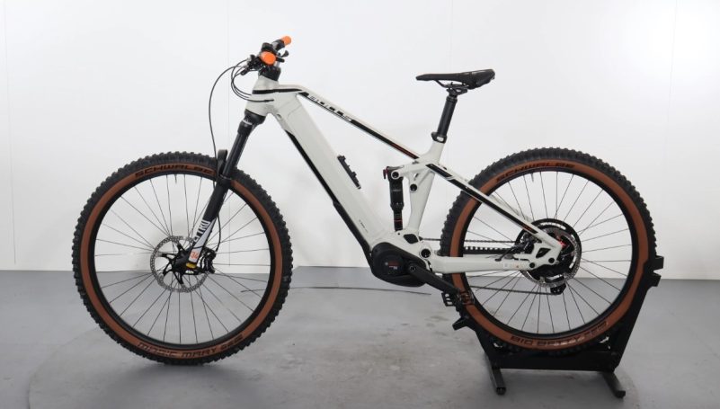 Elektrofahrrad mit braunen Reifen und schwarz-weißem Rahmen, seitliche Ansicht.